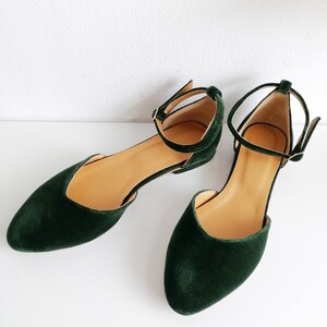 May include: A pair of dark green velvet ankle strap flats with a pointed toe.