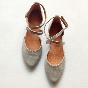 May include: A pair of gray suede ballet flats with criss-cross straps.