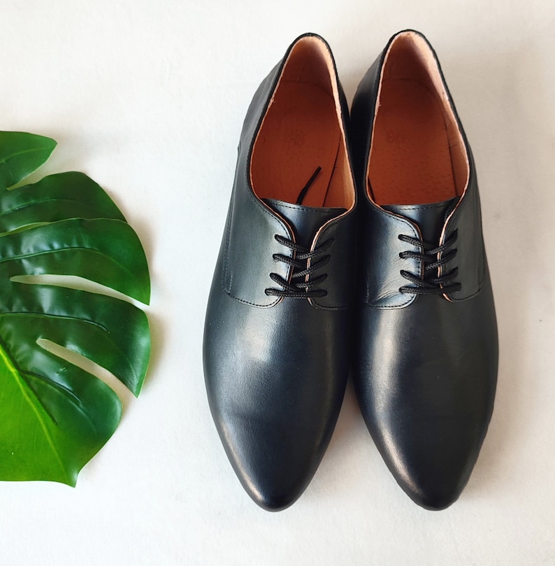 Puede incluir: Un par de zapatos negros de cuero con cordones y puntera puntiaguda.