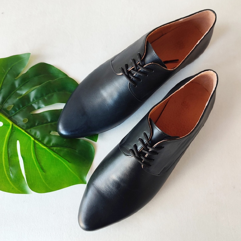 Puede incluir: Dos zapatos negros de cuero con cordones y punta puntiaguda.