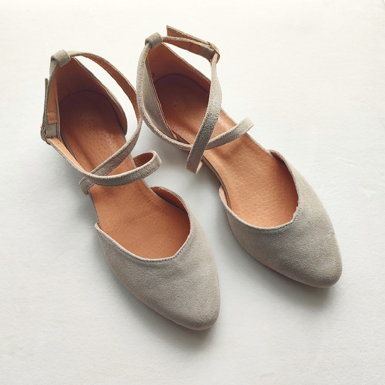 May include: A pair of gray suede ballet flats with criss-cross straps and a pointed toe.