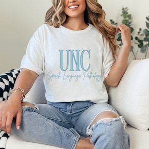 Könnte beinhalten: Weißes T-Shirt mit dem Text "UNC Speech Language Pathology" in blauer Schrift.