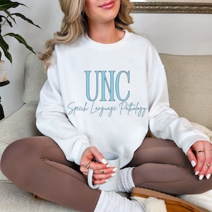 May include: White sweatshirt with the text "UNC Speech Language Pathology" in blue lettering.