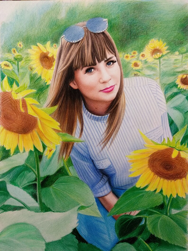 Op de afbeelding: Een vrouw met bruin haar en blauwe ogen draagt een zonnebril en een blauw-wit gestreept shirt. Ze staat in een veld met zonnebloemen.
