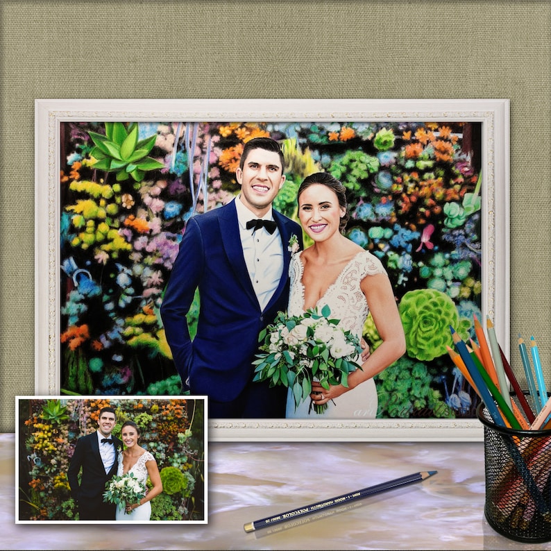 Puede incluir: Una pintura enmarcada de una pareja de bodas de pie frente a una pared de suculentas coloridas. El novio lleva un traje azul y una corbata de mo&ntilde;o negra. La novia lleva un vestido blanco y sostiene un ramo de flores blancas.