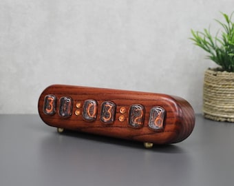 May include: A digital clock with a dark wood finish displays the time 30:03:26. The clock has a rounded rectangular shape and sits on small brass feet. The numbers glow with an orange light.