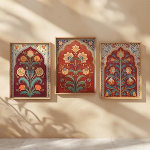 Puede incluir: Tres impresiones artísticas enmarcadas con diseños florales de estilo tradicional. Cada impresión tiene un fondo rojo con un motivo floral central en amarillo, naranja y turquesa. Los marcos son de color madera clara y las impresiones se exhiben en una pared beige.