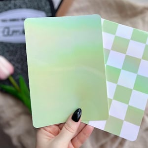 May include: Two iridescent green cardstock sheets. One sheet has a gradient of green and white, the other has a checkered pattern.