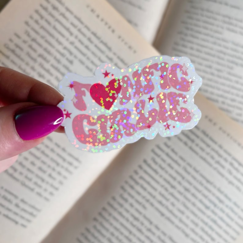 Op de afbeelding: Een witte sticker met een roze en rood glitterontwerp met de tekst "Ik hou van meisjes" met een rood hart in het midden.