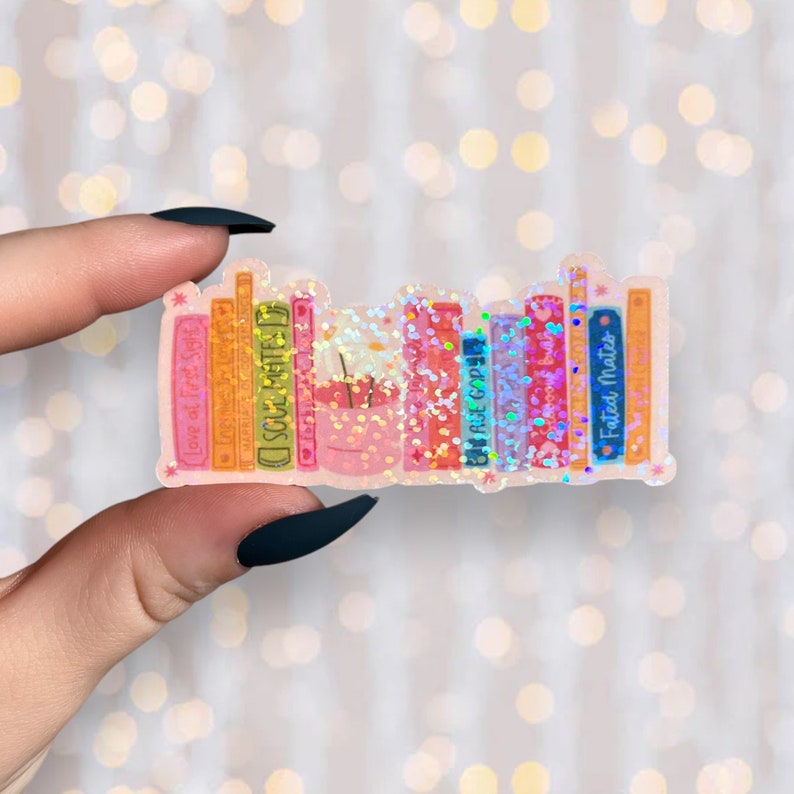 Puede incluir: Una pegatina de una estanter&iacute;a con una variedad de libros coloridos. Los libros tienen t&iacute;tulos como "Love at First Sight", "Soul Mates", "The Recipe" y "Fated Mates". La pegatina tiene un acabado brillante.