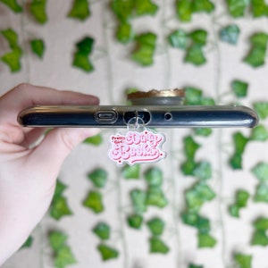 May include: A pink and red phone charm with the text "Pretty Girl! Dirty Books" in a retro font.