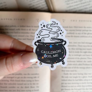 May include: A white sticker with a black cauldron and steam coming out of it. The cauldron has the text "Cauldron Boil Me" on it.