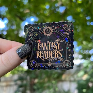 May include: A black and gold sticker with a glittery finish. The sticker features a crescent moon, stars, and the text "The Fantasy Readers Book Club".