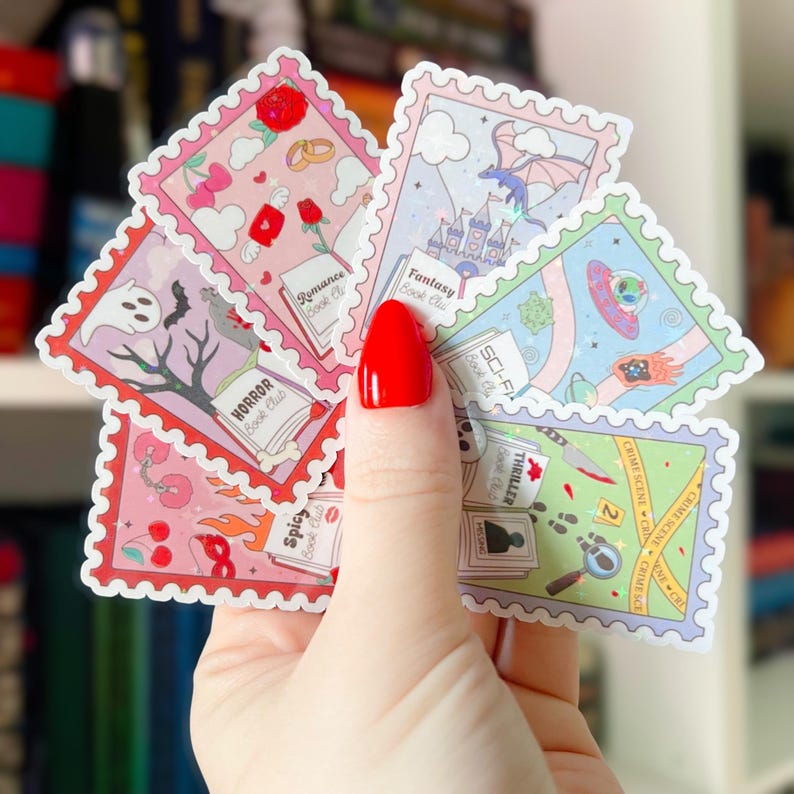 Puede incluir: Una mano sostiene una colecci&oacute;n de pegatinas coloridas con dise&ntilde;os de sellos postales. Cada pegatina presenta un tema diferente, incluyendo clubes de lectura de romance, fantas&iacute;a, terror, ciencia ficci&oacute;n, thriller y picante. Las pegatinas tienen un borde blanco y bordes decorativos.