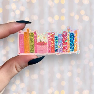 Puede incluir: Una pegatina de una estanter&iacute;a con una variedad de libros coloridos, cada uno con un t&iacute;tulo diferente. Los libros est&aacute;n cubiertos de purpurina y tienen un brillo arco&iacute;ris. Hay una peque&ntilde;a maceta rosa con una manzana roja encima de los libros.