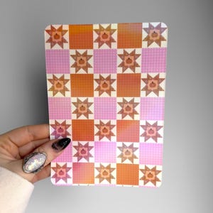 May include: A rectangular sticker featuring a repeating checkerboard pattern of orange squares with star-shaped pumpkin motifs and light pink squares with a subtle white grid pattern. The design alternates between these two distinct square types.