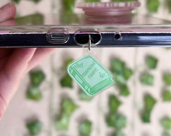 May include: A green and white phone charm with the text "Dreamione Fanfic" on a book-shaped design.