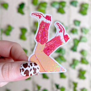 May include: A sticker of a pair of legs in red cowboy boots with a sparkly iridescent background.