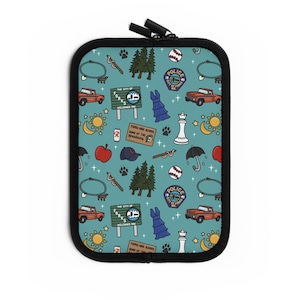 May include: Teal zippered case with a repeating pattern of illustrations. The pattern includes a red truck, a police badge, a dress, a chess piece, a baseball, a sign that says "The City of Forks Welcomes You", and other themed images.