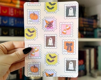 May include: A rectangular Halloween-themed sticker sheet featuring postage stamp designs. The stamps showcase pumpkins, bats, ghosts, candy corn, and a witch cat. Each stamp has a decorative border and a price value.