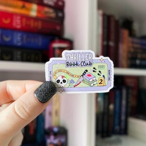 May include: A sticker with the text "Thriller Book Club" in a ticket design. The sticker features a skull, a bloody knife, books, and footprints. The background is a bookshelf with various books.