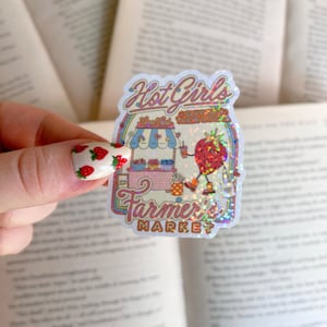 May include: A holographic sticker with a cartoon strawberry holding a drink and standing in front of a pink and blue farmer's market stand. The sticker says "Hot Girls Support Their Local Farmer's Market".