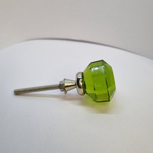 Könnte beinhalten: Ein grüner Glas-Schrankknopf mit silberner Basis und einer Schraube.