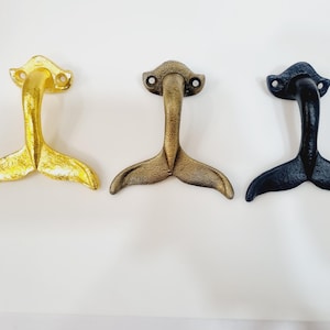 May include: Three metal mermaid tail hooks in gold, bronze, and black.