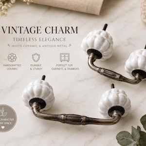 May include: Two drawer pulls featuring white ceramic pumpkin-shaped knobs attached to curved antique metal handles. The text VINTAGE CHARM, TIMELESS ELEGANCE, WHITE CERAMIC & ANTIQUE METAL, HANDCRAFTED CERAMIC, DURABLE & STURDY, PERFECT FOR CABINETS & DRAWERS is visible.