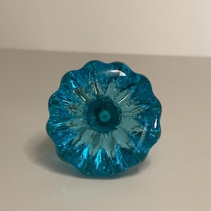 Pode incluir: Um botão de armário de vidro azul turquesa com um design canelado.