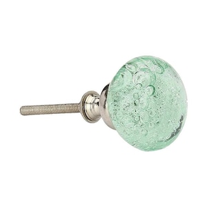 May include: A round cabinet knob featuring a translucent light green glass head with embedded air bubbles of varying sizes. The knob is attached to a silver-toned metal base and a threaded bolt, providing a functional hardware component.