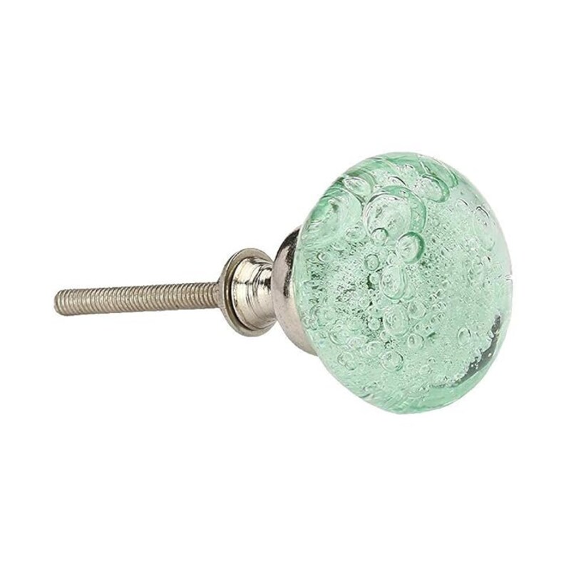 May include: A round cabinet knob featuring a translucent light green glass head with embedded air bubbles of varying sizes. The knob is attached to a silver-toned metal base and a threaded bolt, providing a functional hardware component.