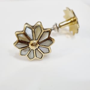 以下が含まれることがあります： 花の形をした金色のキャビネットノブ。花は白い真珠貝で作られており、金色のセンターがあります。