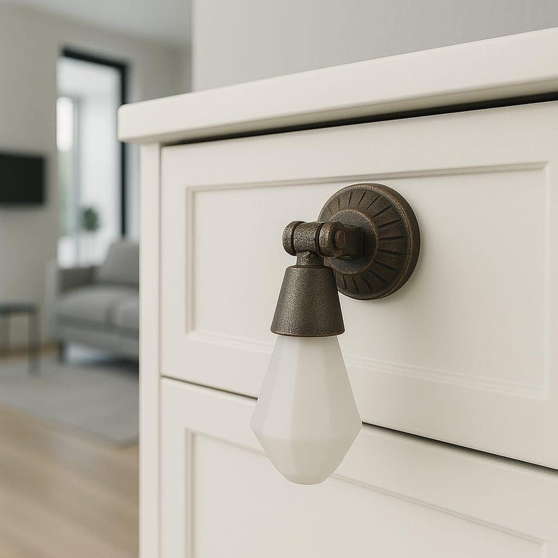 May include: A wall-mounted light fixture featuring a circular, dark bronze-toned metal base with a radial pattern, a hinged arm, and a downward-facing, faceted, opaque white glass shade shaped like a geometric teardrop or pendant bulb.
