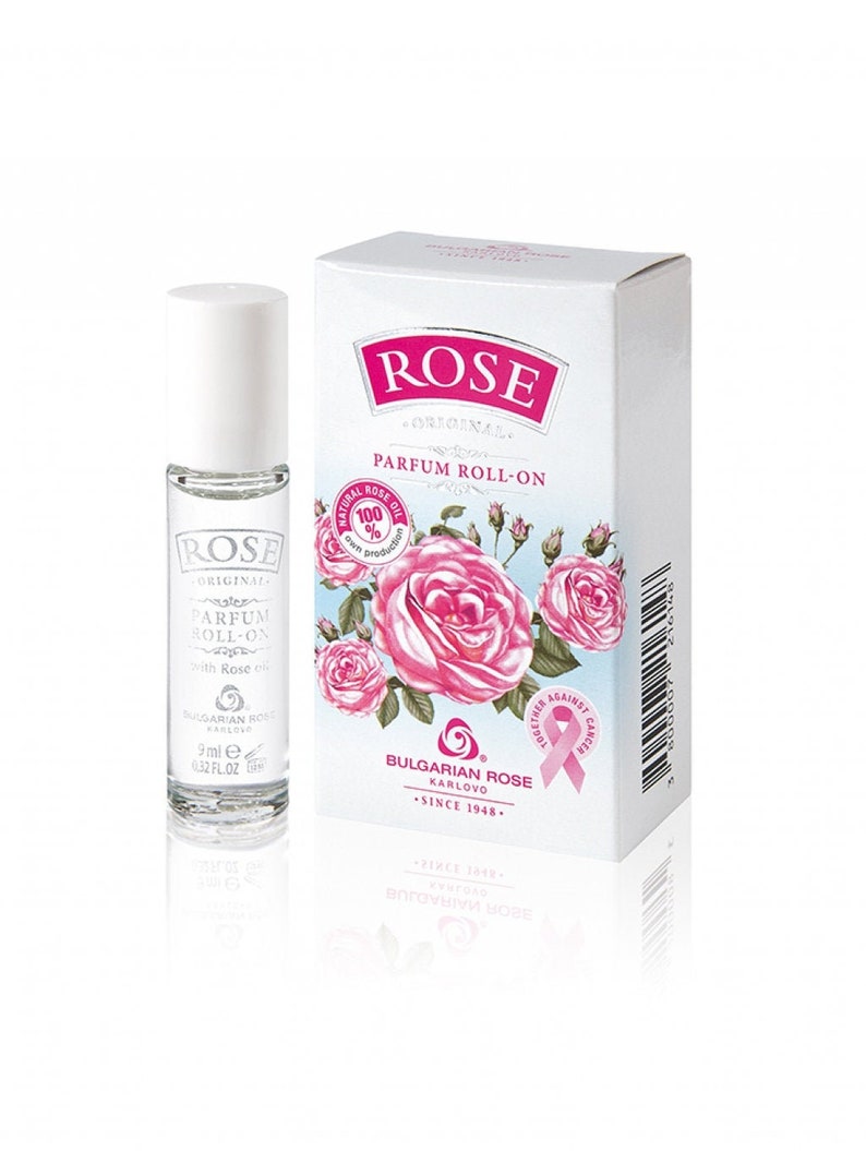 May include: A clear glass roll-on perfume bottle and a white box. The bottle has a white cap and the text "ROSE ORIGINAL PARFUM ROLL-ON". The box features pink roses, the word "ROSE", and the text "BULGARIAN ROSE KARLOVO".