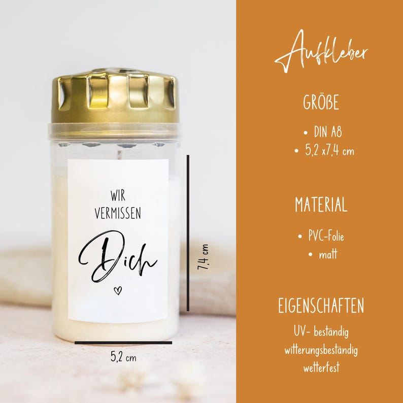 May include: A white candle with a gold lid and a sticker that reads "Wir vermissen Dich" (We miss you) in black lettering. The candle is 7.4 inches tall and 5.2 inches wide.