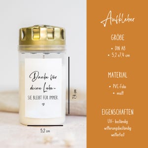 Puede incluir: Una pegatina blanca con texto negro que dice "Danke f&uuml;r deine Liebe - SIE BLEIBT F&Uuml;R IMMER." con un peque&ntilde;o s&iacute;mbolo de coraz&oacute;n. La pegatina est&aacute; pegada a un frasco de vidrio transparente con tapa dorada. El frasco mide 7,4 cm de alto y 5,2 cm de ancho.
