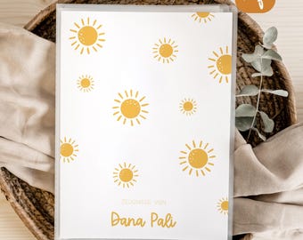 May include: A clear plastic document folder featuring a white cover decorated with yellow sun illustrations of varying sizes. The text "ZEUGNISSE VON" is printed in small letters above the name "DANA PALI" in a larger, bold yellow script font.