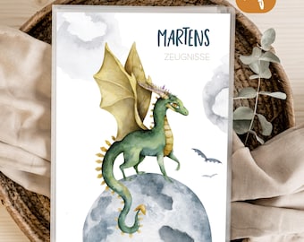 May include: A document folder featuring a watercolour illustration of a green dragon with yellow wings standing on a grey moon. The text MARTENS ZEUGNISSE is printed in dark blue at the top. Two small dark bats are flying in the white background.