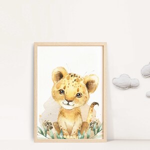 May include: A watercolor illustration of a cute, cartoon lion cub with brown spots sitting in a patch of green leaves. The lion cub is looking at the viewer with a friendly expression. The background is white.