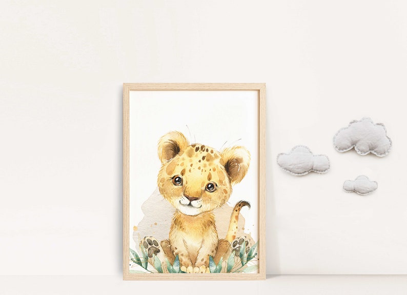 May include: A watercolor illustration of a cute, cartoon lion cub with brown spots sitting in a patch of green leaves. The lion cub is looking at the viewer with a friendly expression. The background is white.
