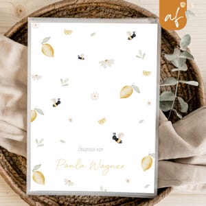Könnte beinhalten: Ein weißer Ordner mit einem Zitronen- und Bienen-Motiv. Der Ordner trägt den Text "Zeugnisse von Paula Wagner" auf der Vorderseite.