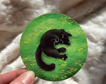Black cat cute vinyl sticker in a meadow