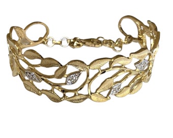 May include: A gold bracelet with a delicate leaf design and small clear stones. The bracelet is open and has a clasp.