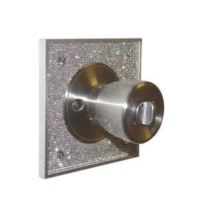 May include: A silver door knob with a square base covered in rhinestones. The knob has a silver finish and a keyhole.