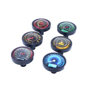 May include: Six different black and silver motorcycle gauge knobs with various colored faces and designs. The gauges include a speedometer, tachometer, and fuel gauge.