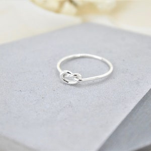 A silver knot ring on a gray background.