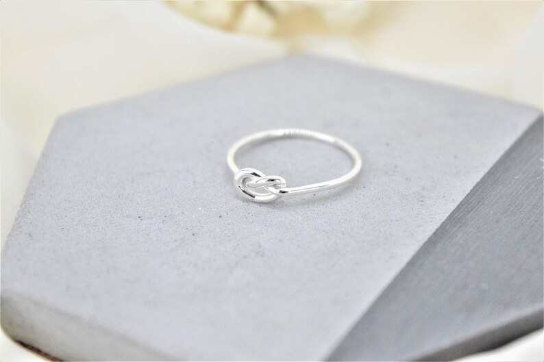 A silver knot ring on a gray background.