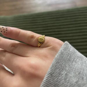 A gold ring with an oval-shaped setting featuring the letter 'A' in black lettering.