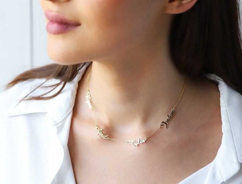 A gold necklace with four names, "Rylan", "April", "Taylor", and "Judah", spelled out in cursive.
